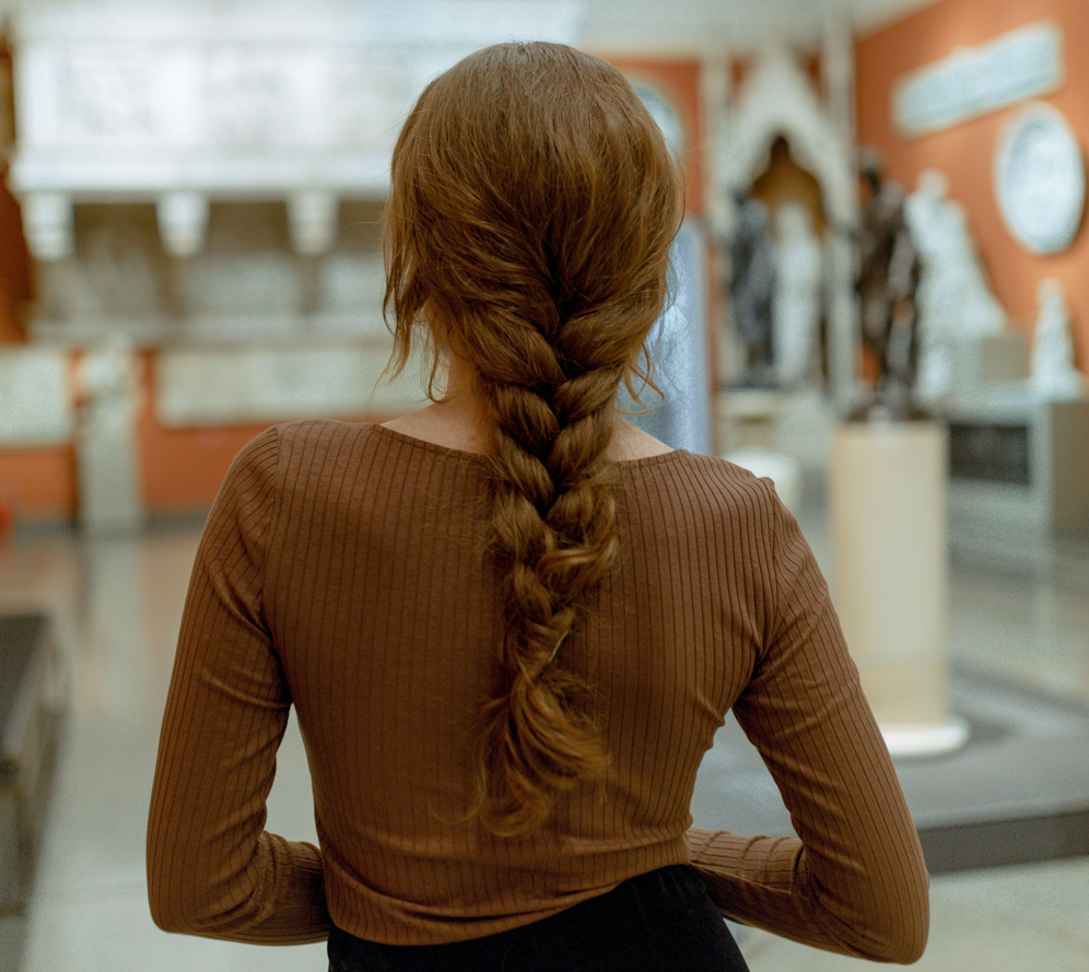 A woman with brown hair in a braid down her back. Concept of hair styles for thinning hair.