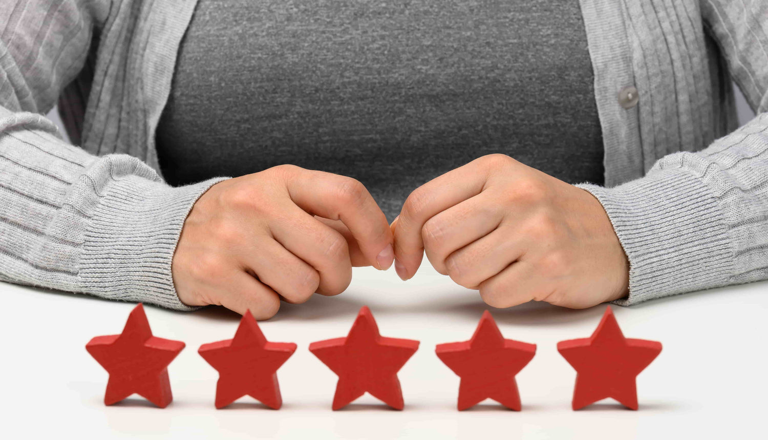 A woman sitting in front of five wooden stars, implying hair fiber reviews and ratings.